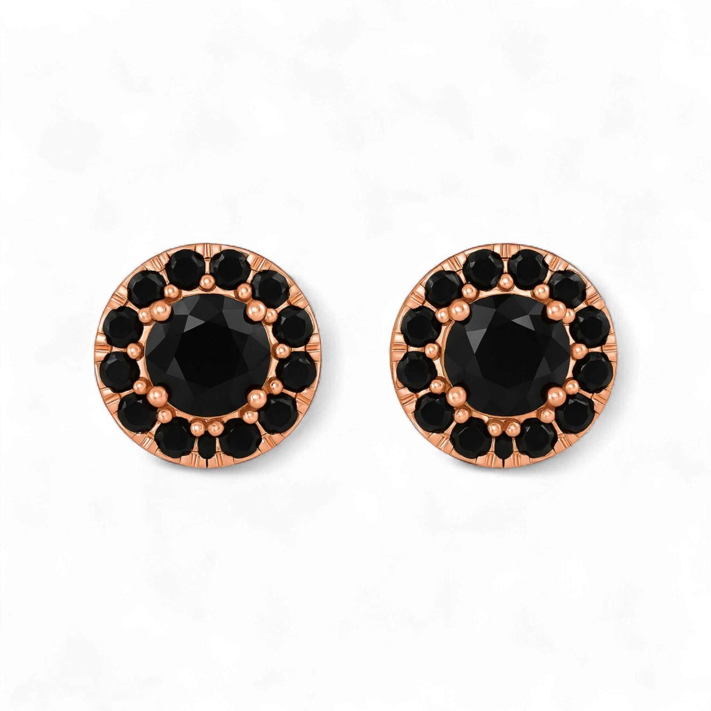 Pair of round earrings with black gemstones and rose gold frames on a white background