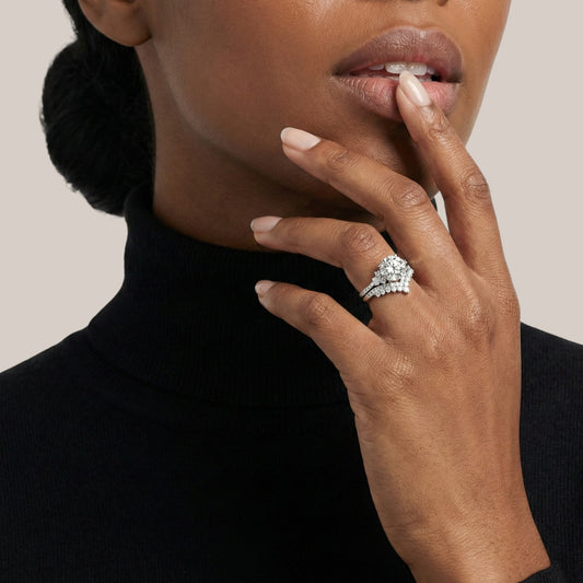 Woman wearing a diamond ring on her finger with a neutral background