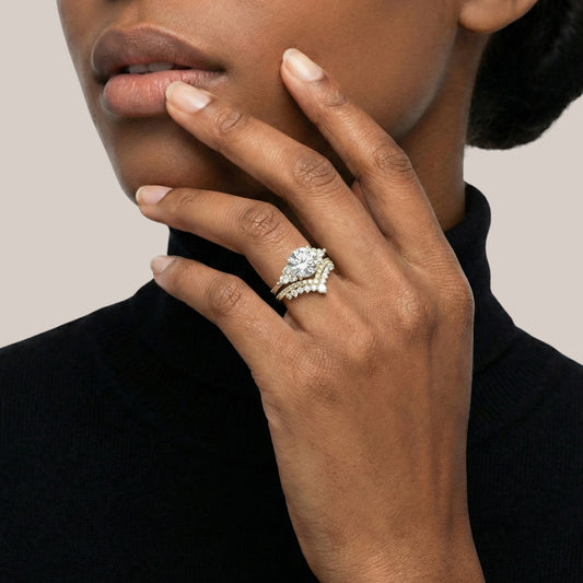 Close-up of a hand wearing a diamond ring on a neutral background