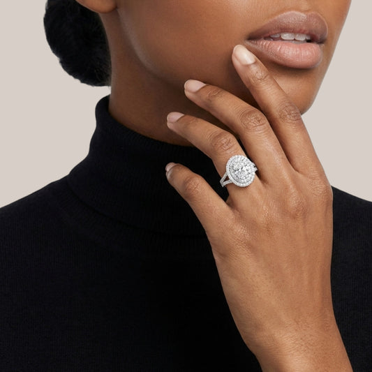 Close-up of a person wearing a diamond ring on a plain background