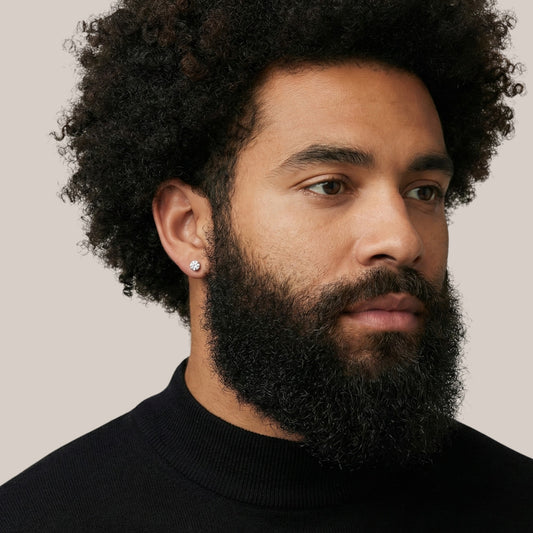 Man with a beard and curly hair wearing a black turtleneck against a neutral background