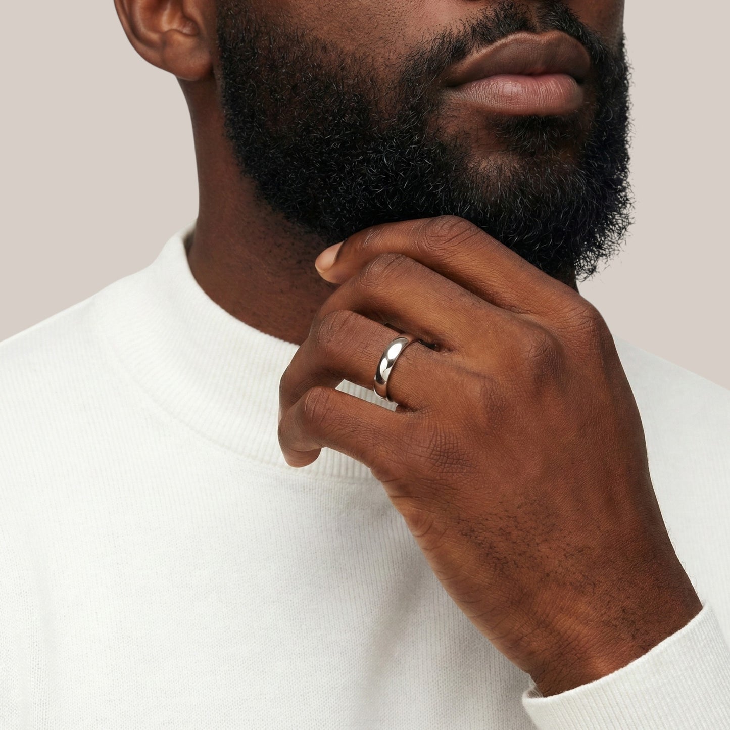 Man wearing a silver ring on his finger with a neutral background