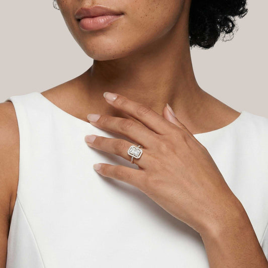 Woman wearing a diamond ring on her hand against a neutral background