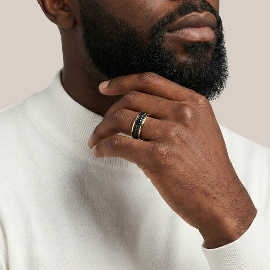 Man wearing a white turtleneck sweater with a close-up of his hand and ring.