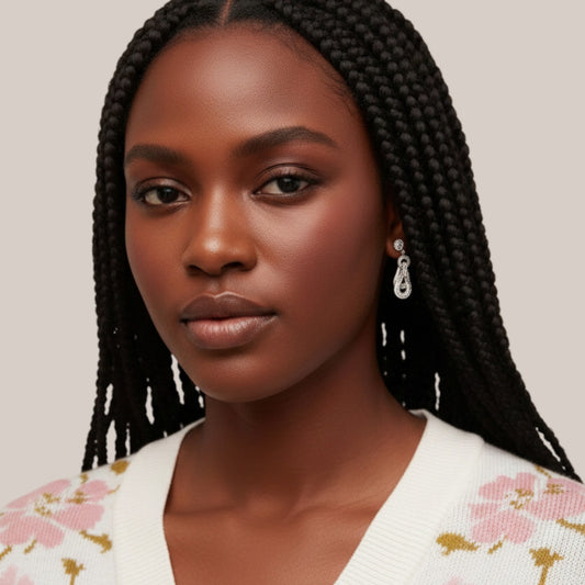 Woman with braided hair wearing a white floral cardigan against a plain background
