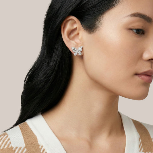 Close-up of a woman wearing butterfly-shaped earrings with a neutral background