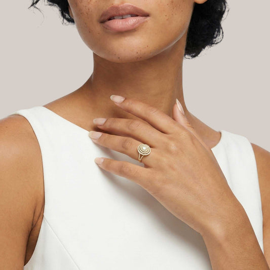 Woman wearing a gold ring on her hand with a plain background