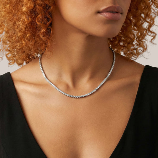 Woman wearing a silver necklace against a neutral background