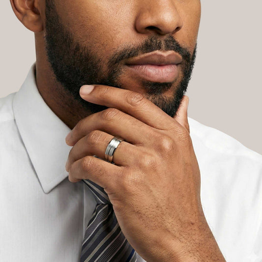 Man wearing a white shirt and striped tie with a close-up of his hand and ring.