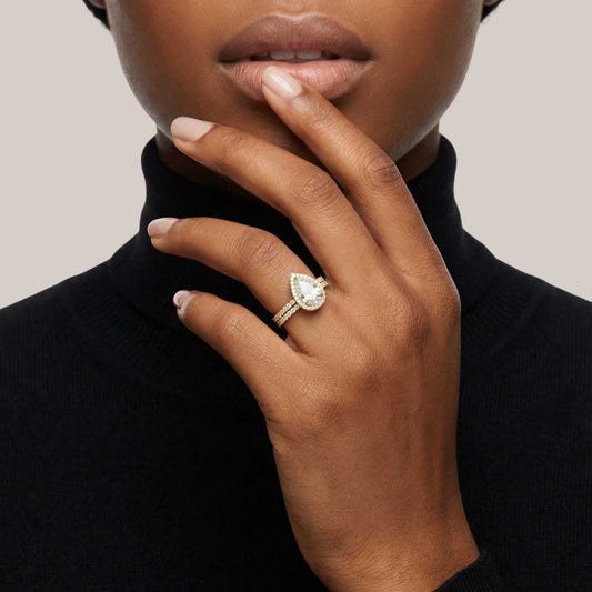 Close-up of a hand wearing a diamond ring with a neutral background