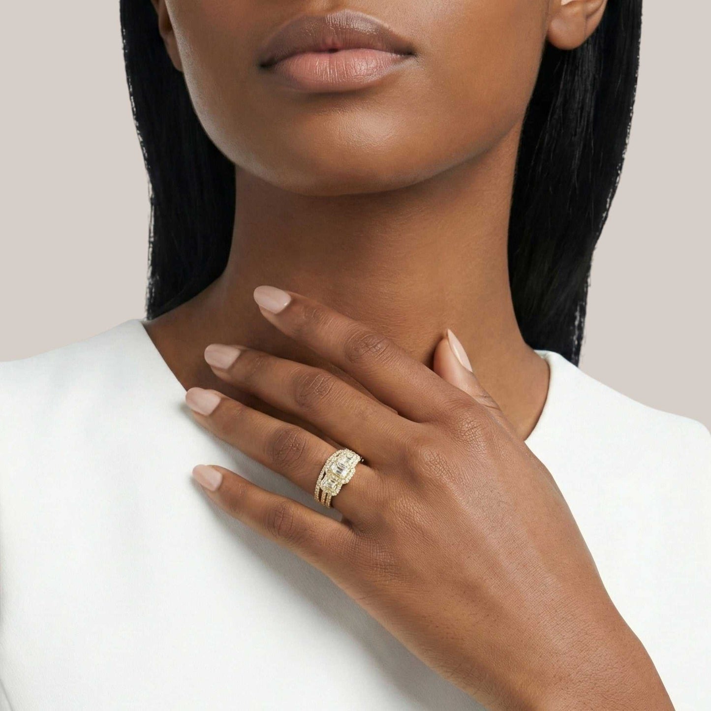 Woman wearing a gold ring on her hand with a plain background