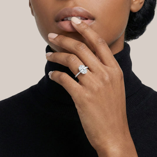 Woman wearing a diamond ring on her finger against a neutral background
