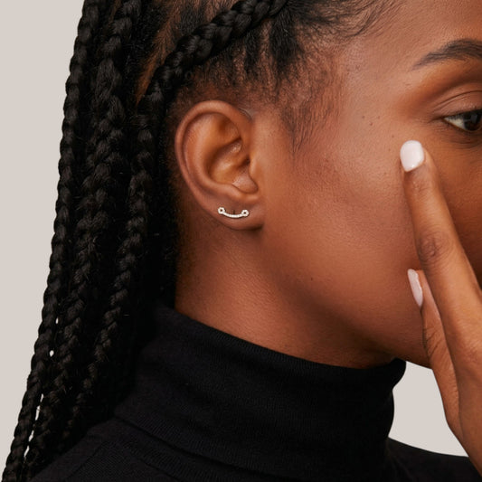 Close-up of a person with braided hair wearing a black turtleneck against a neutral background