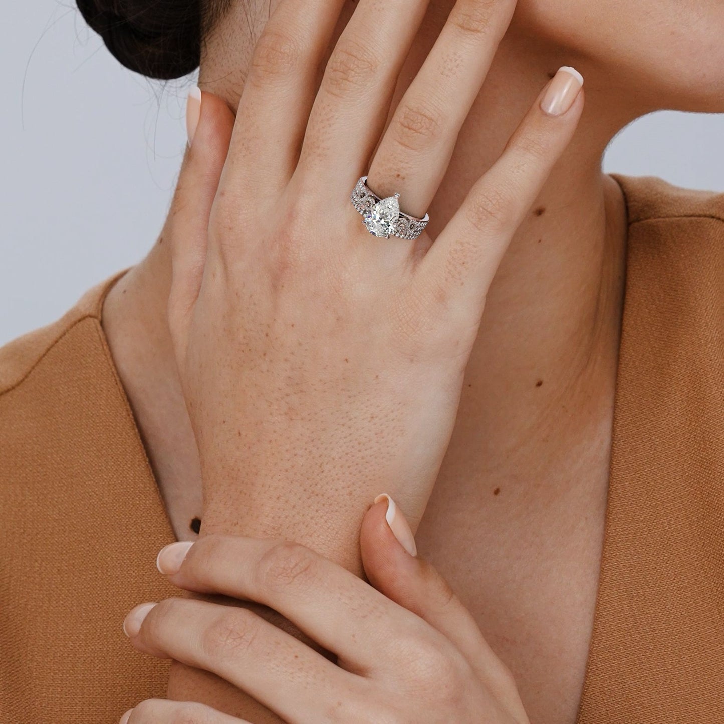 Close-up of a hand wearing a diamond ring with a neutral background