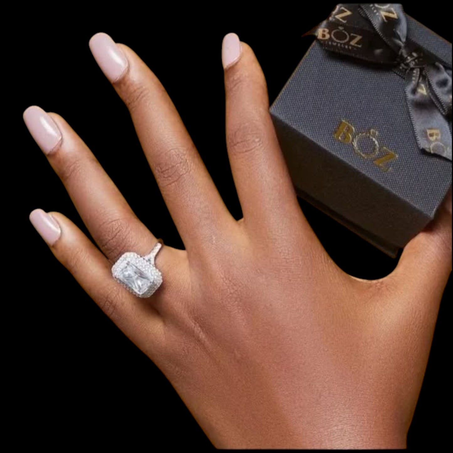 Hand wearing a diamond ring with a BOZ box in the background