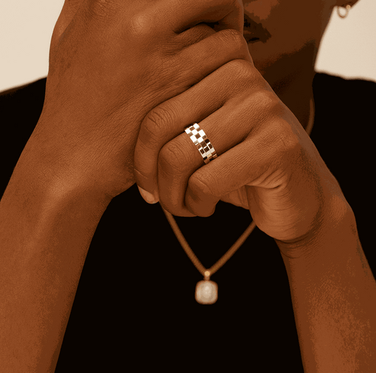 Close-up of a hand wearing a gold ring with a necklace featuring a pearl pendant.