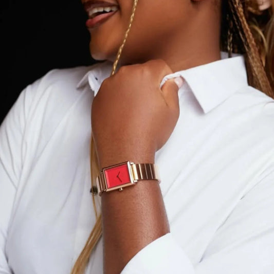 Woman wearing a red watch with a gold band on a white background