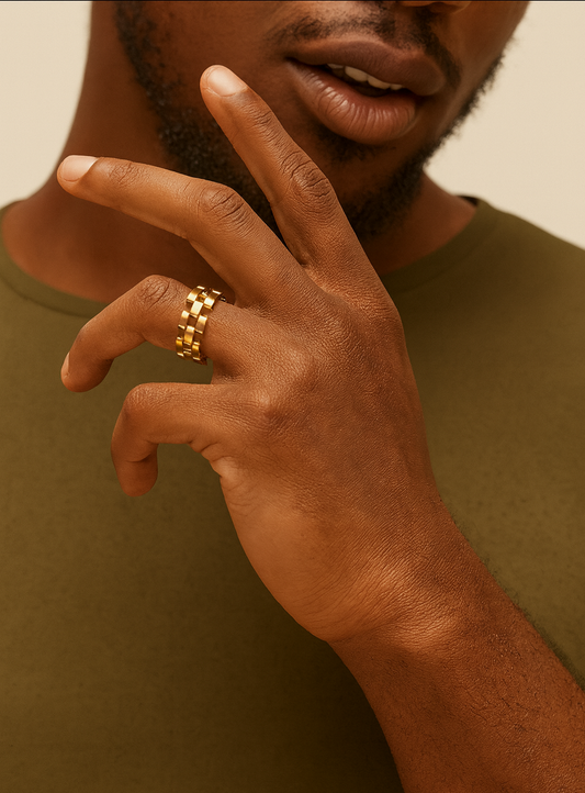 Close-up of a hand with a gold ring on a neutral background