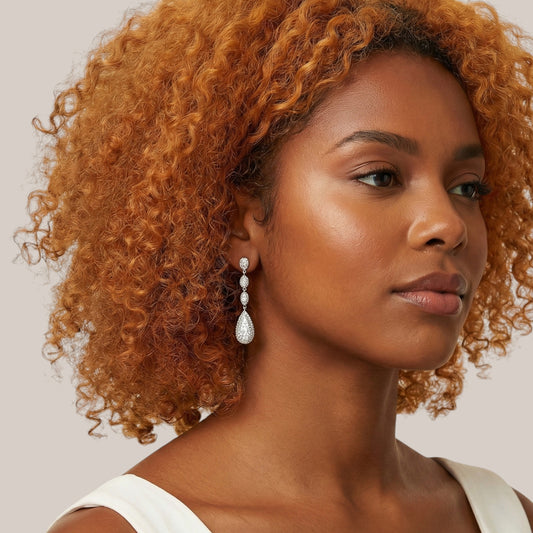 Woman with curly hair wearing a white top against a neutral background