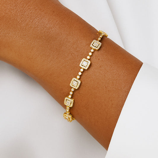 Gold bracelet with square and round beads on a wrist against a white background