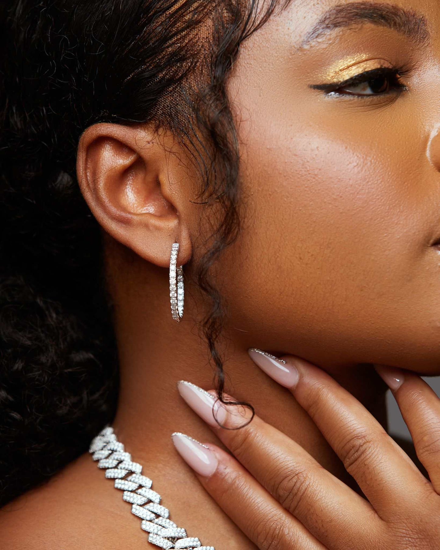 Close-up of woman's ear wearing icy moissanite hoop earrings in 925 sterling silver with sparkling stones