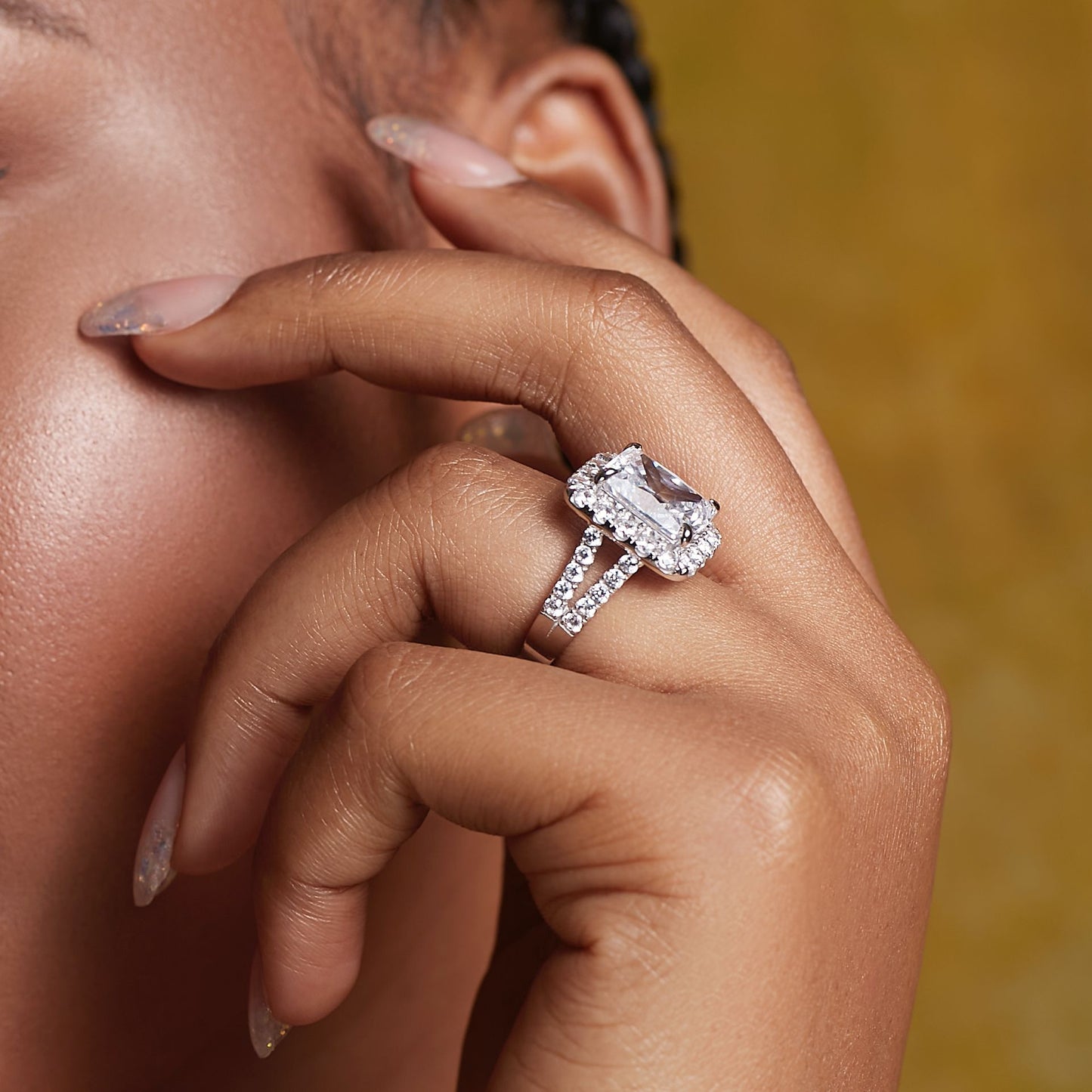 Close-up of a hand wearing a diamond ring with a blurred background