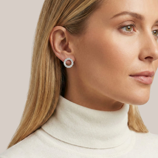 Close-up of a woman wearing a silver hoop earring against a light background