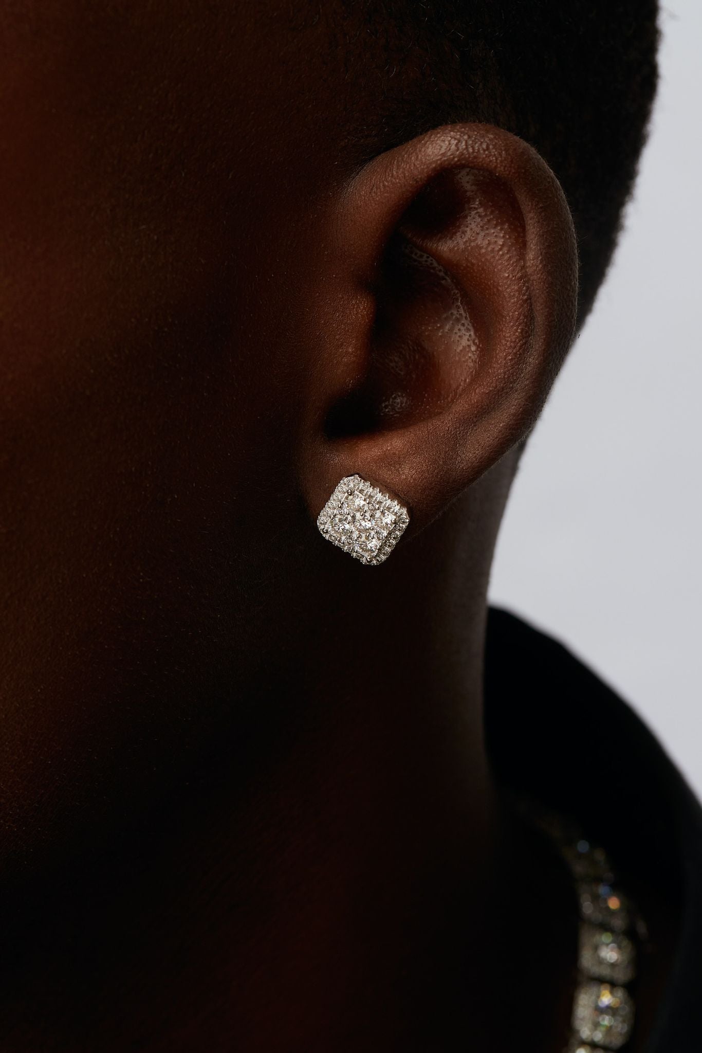 A close-up image of a person's ear wearing a stud earring, with the rest of the ear and head out of view.