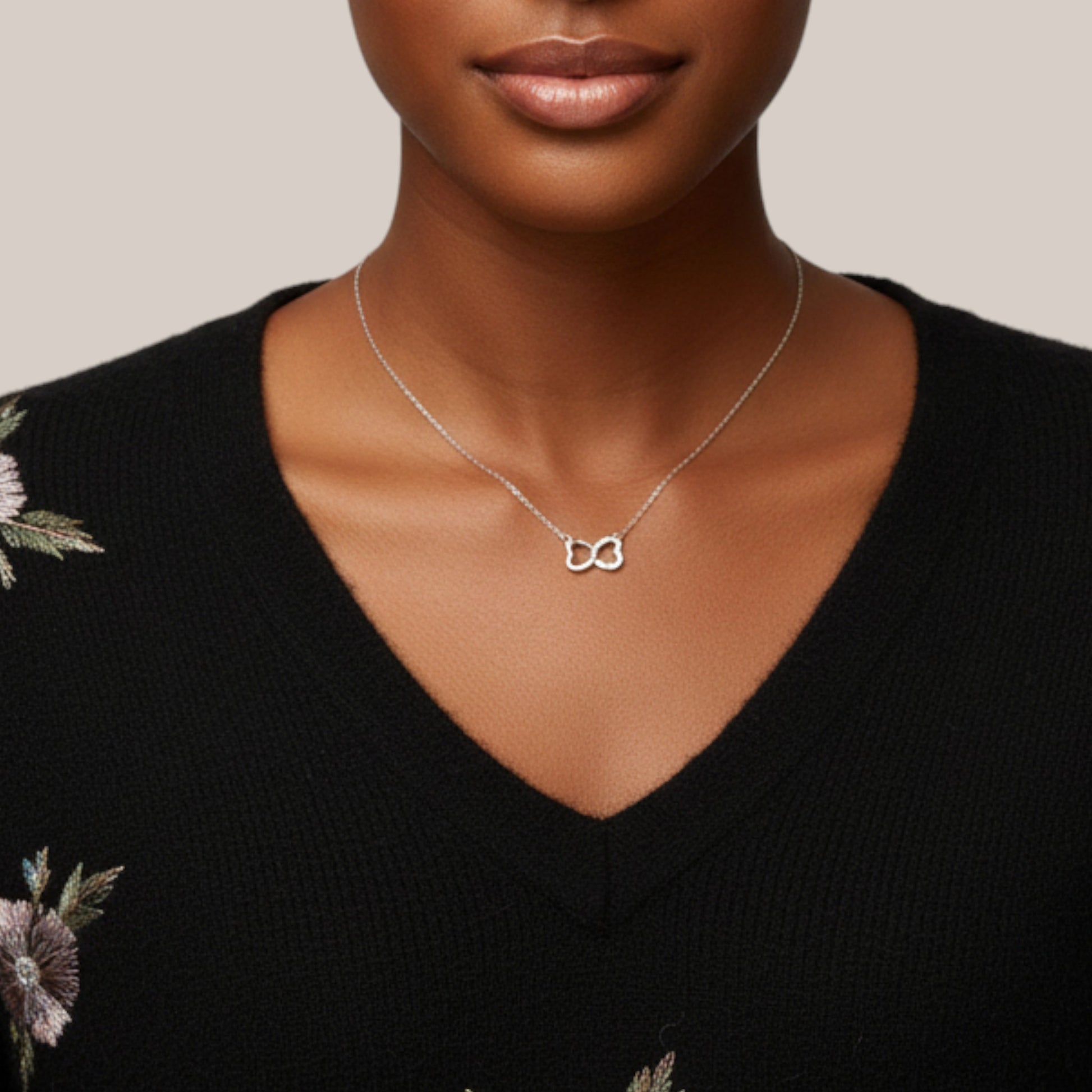 Woman wearing a silver necklace with a unique pendant against a neutral background
