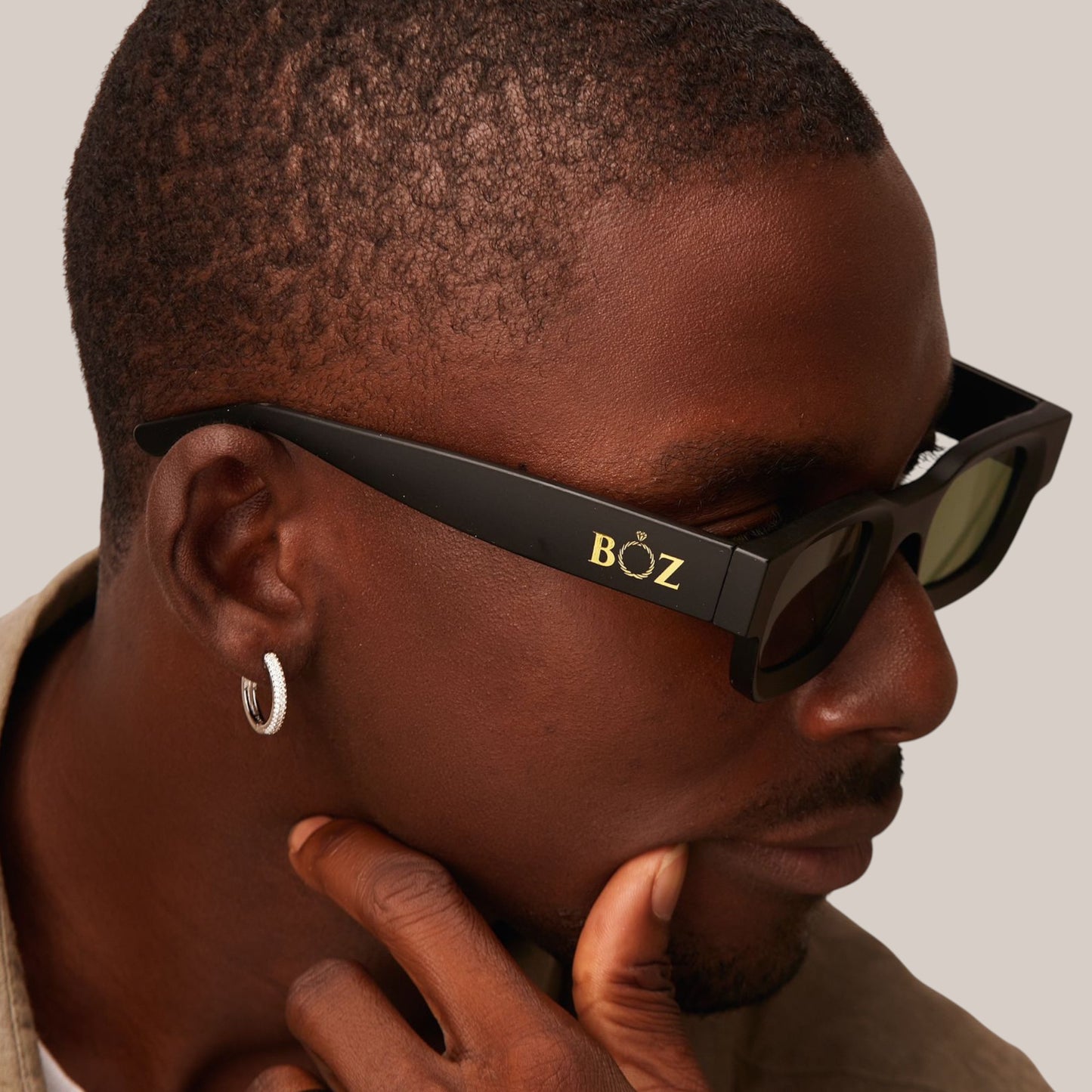Man wearing black sunglasses with 'BOZ' logo, looking to the side.