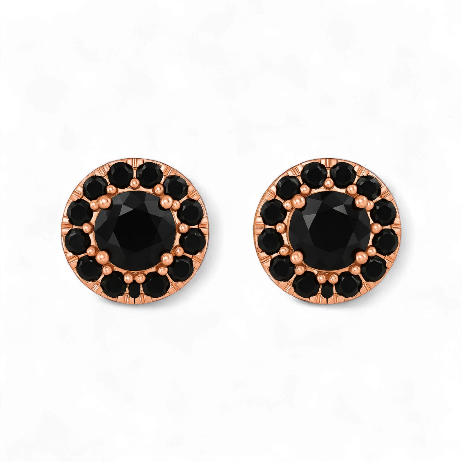 Pair of round earrings with black gemstones and rose gold frames on a white background