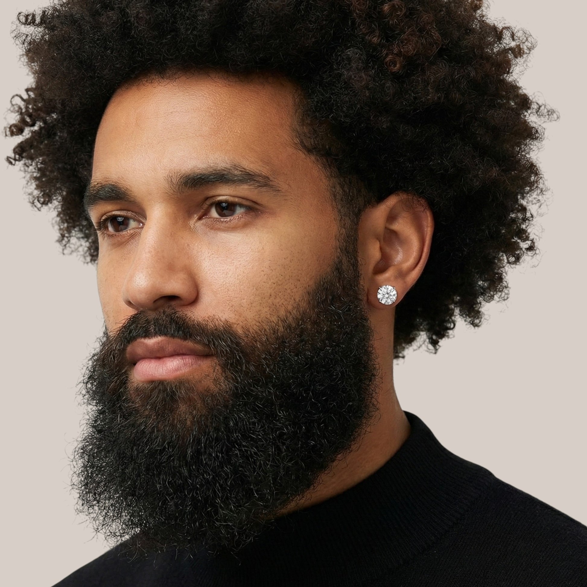 Man with a beard wearing a diamond earring against a neutral background
