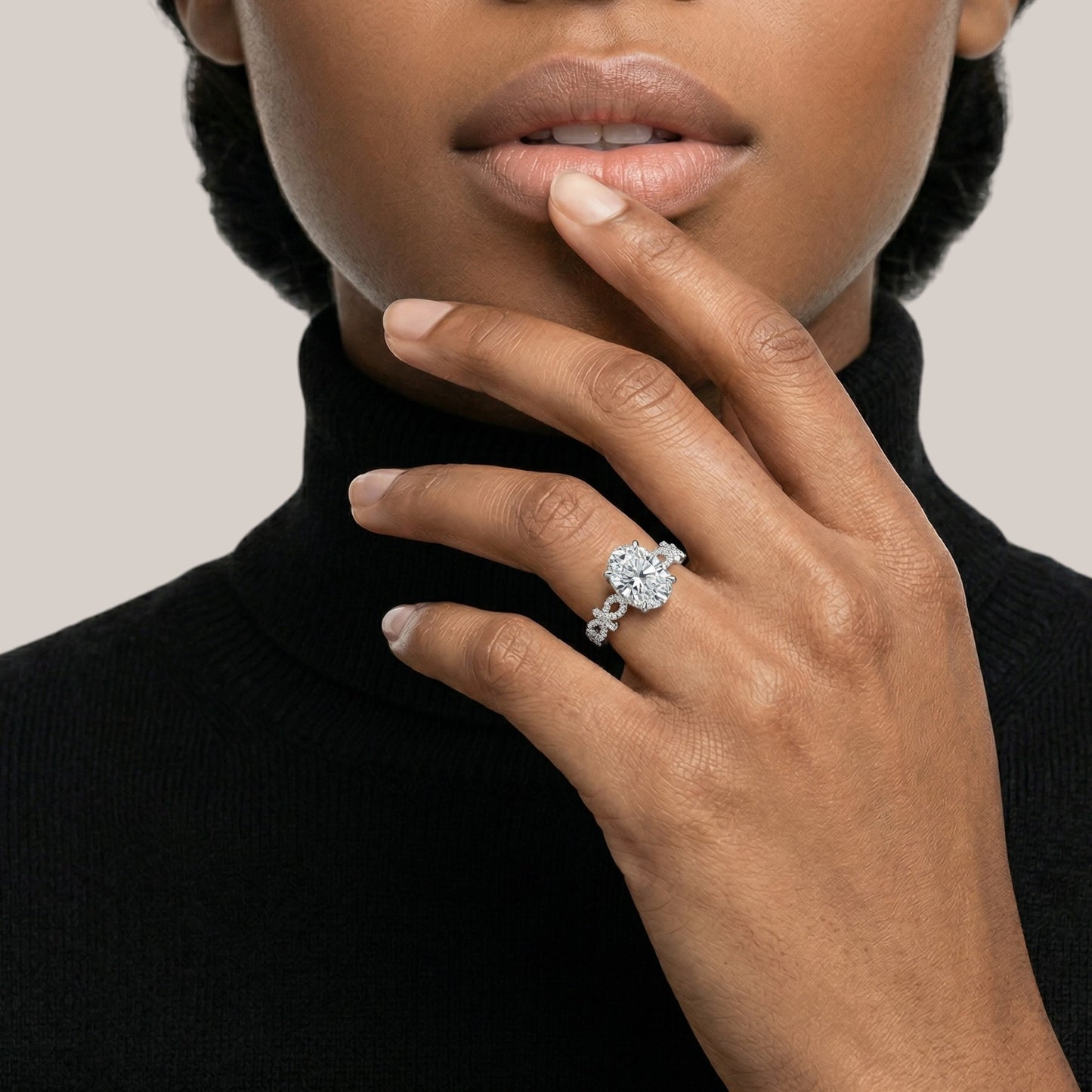 Close-up of a hand wearing a diamond ring with a neutral background