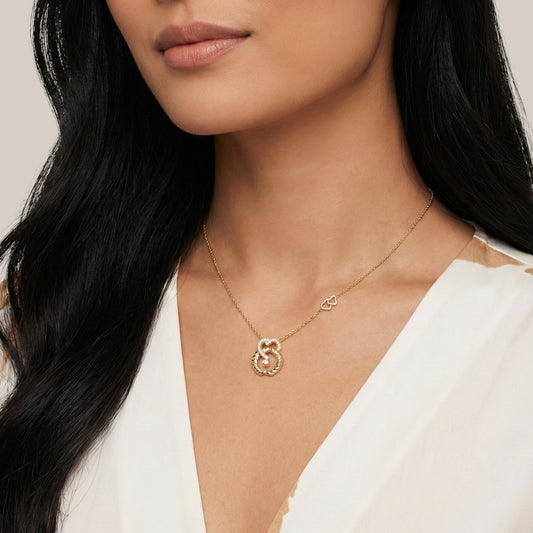 Woman wearing a gold necklace with a heart and infinity symbol pendant.