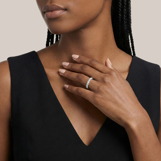 Woman wearing a black sleeveless top with a close-up of her hand and ring.