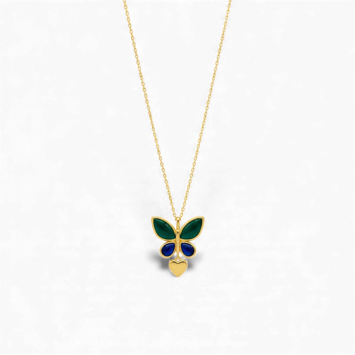 Butterfly-shaped pendant on a gold chain against a white background