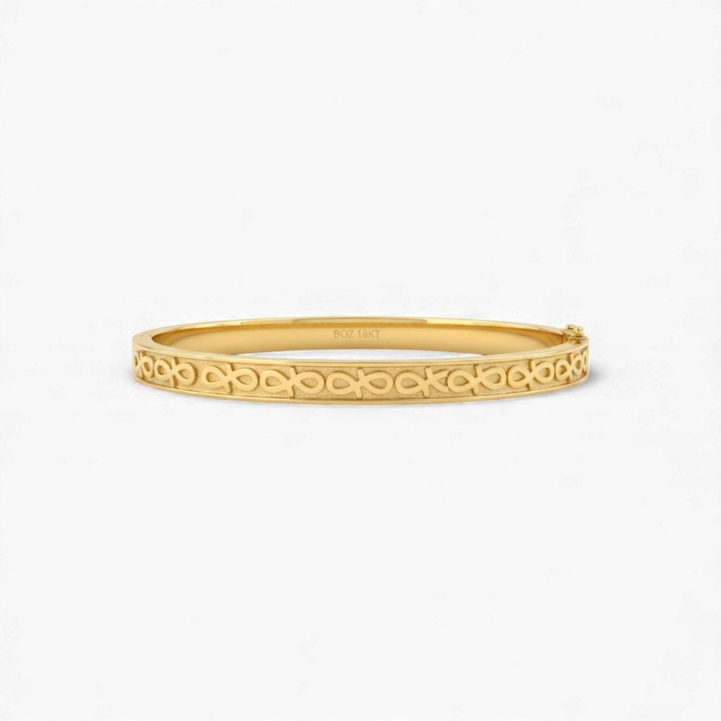 Gold bangle with intricate design on a white background