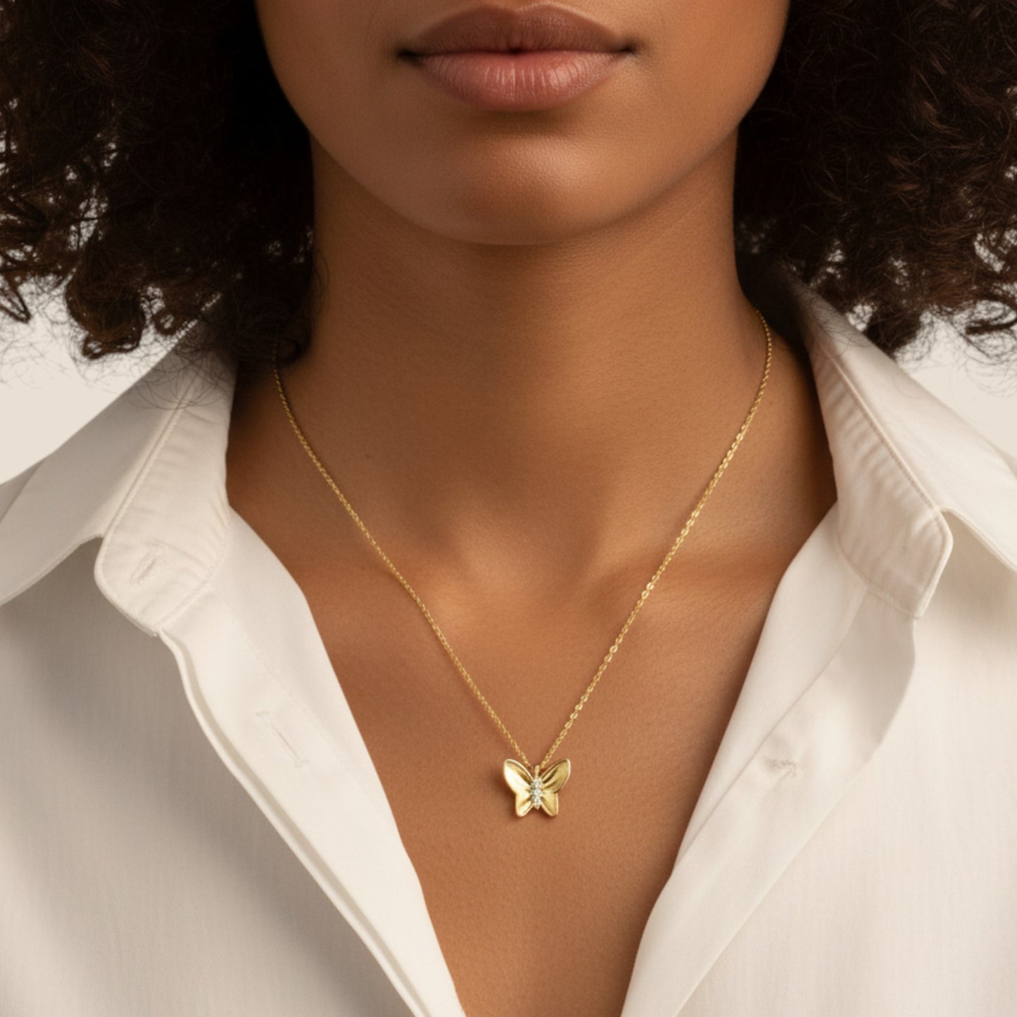 Woman wearing a gold butterfly necklace with a white shirt