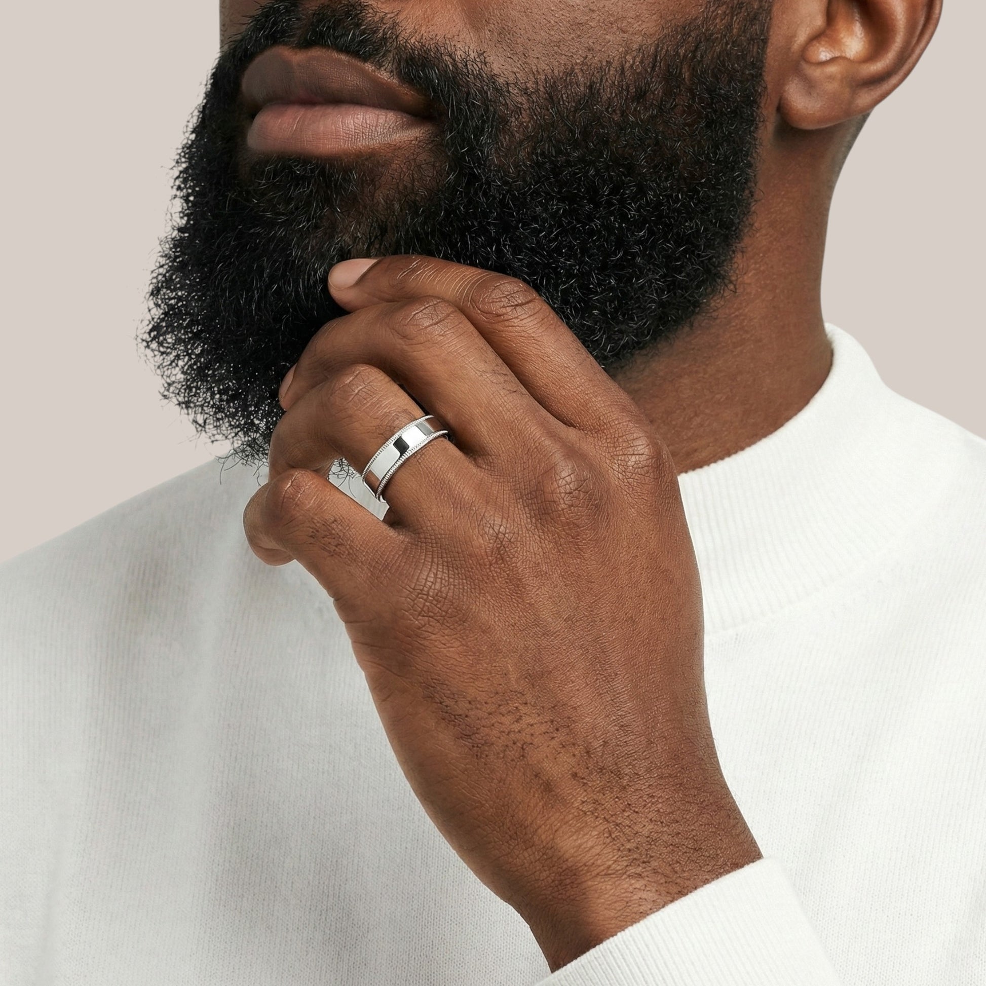 Man wearing a silver ring on his finger with a neutral background