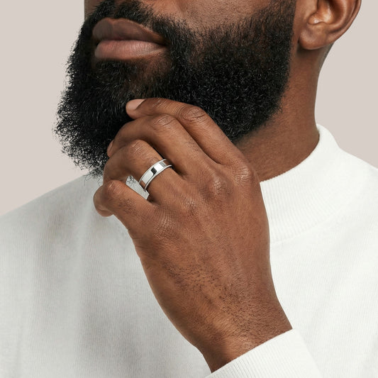Man wearing a silver ring on his finger with a neutral background
