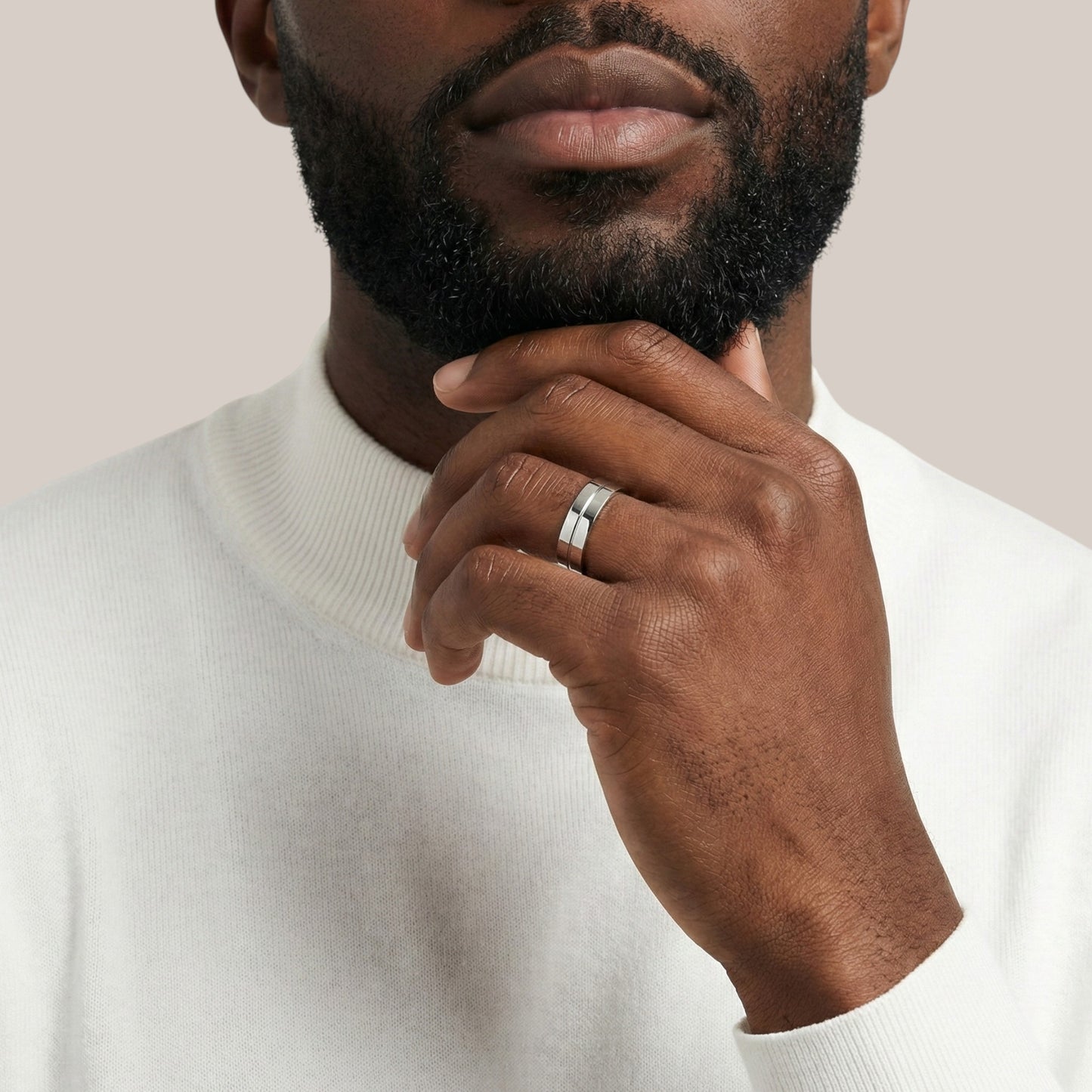 Man wearing a white sweater with a neutral background