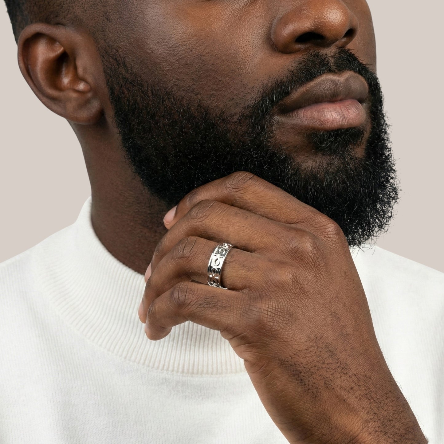 Man wearing a silver ring on his finger with a neutral background