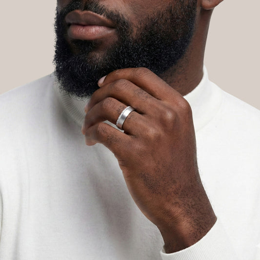 Man wearing a silver ring on his finger, with a neutral background