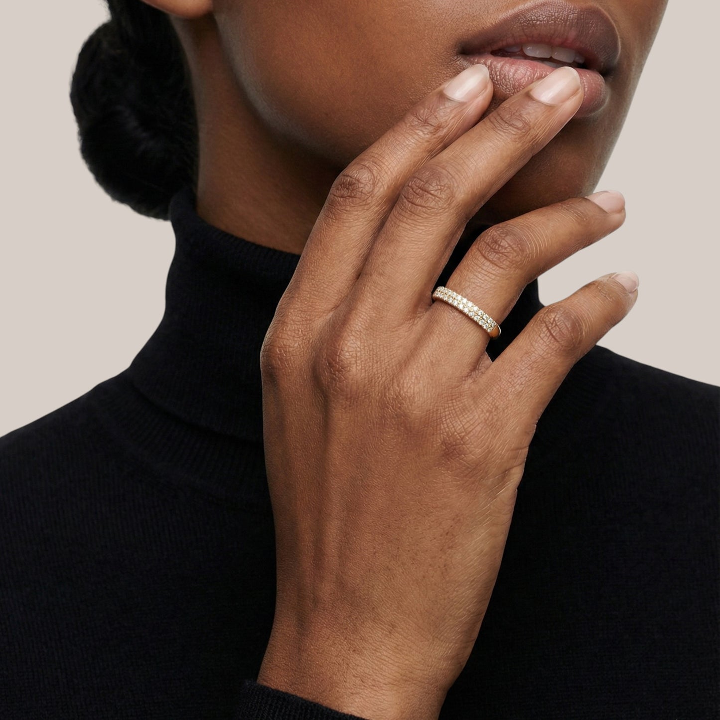 Close-up of a hand wearing a ring with a neutral background