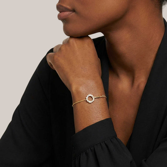 Woman wearing a gold bracelet on a neutral background