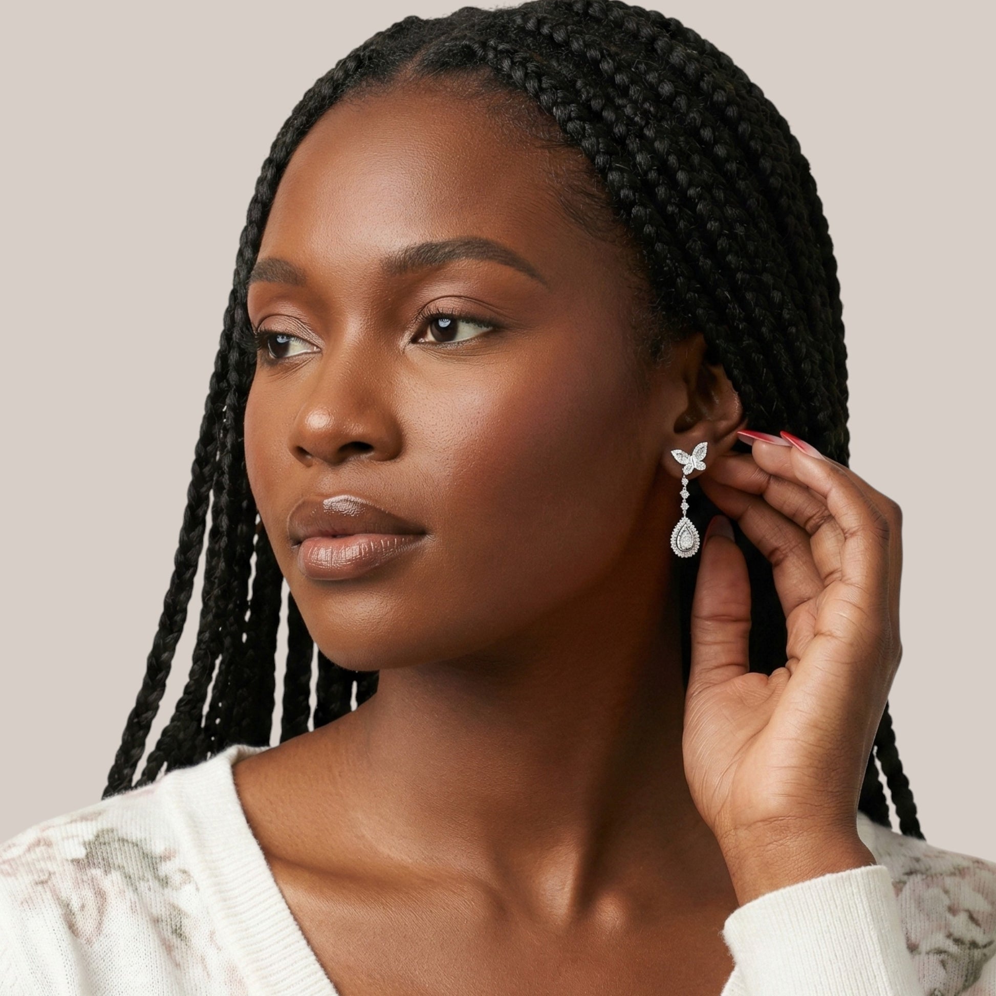 Woman adjusting an earring with a neutral background