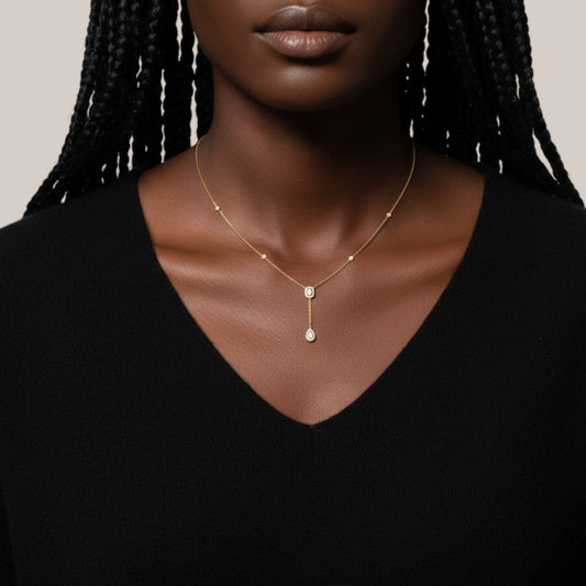 Woman wearing a gold necklace with a pendant against a neutral background