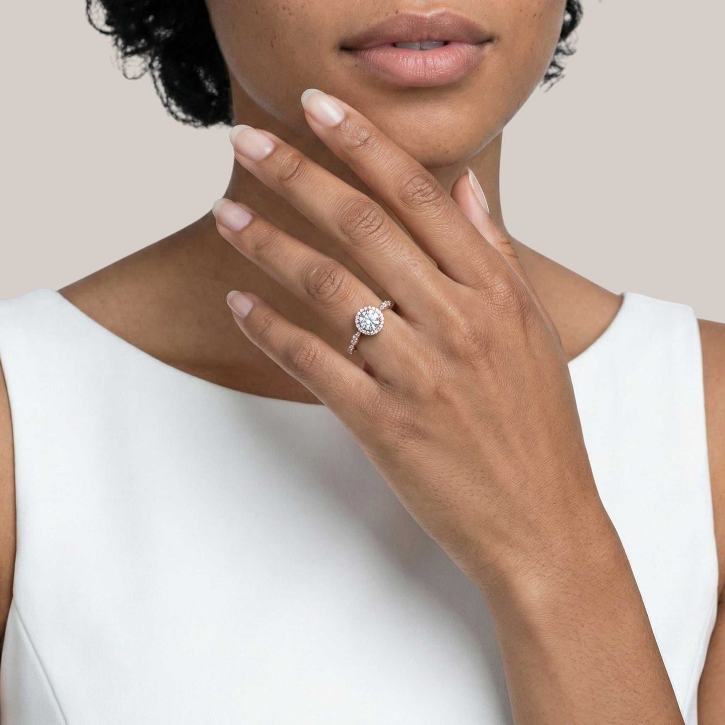Close-up of a hand wearing a diamond ring with a plain background