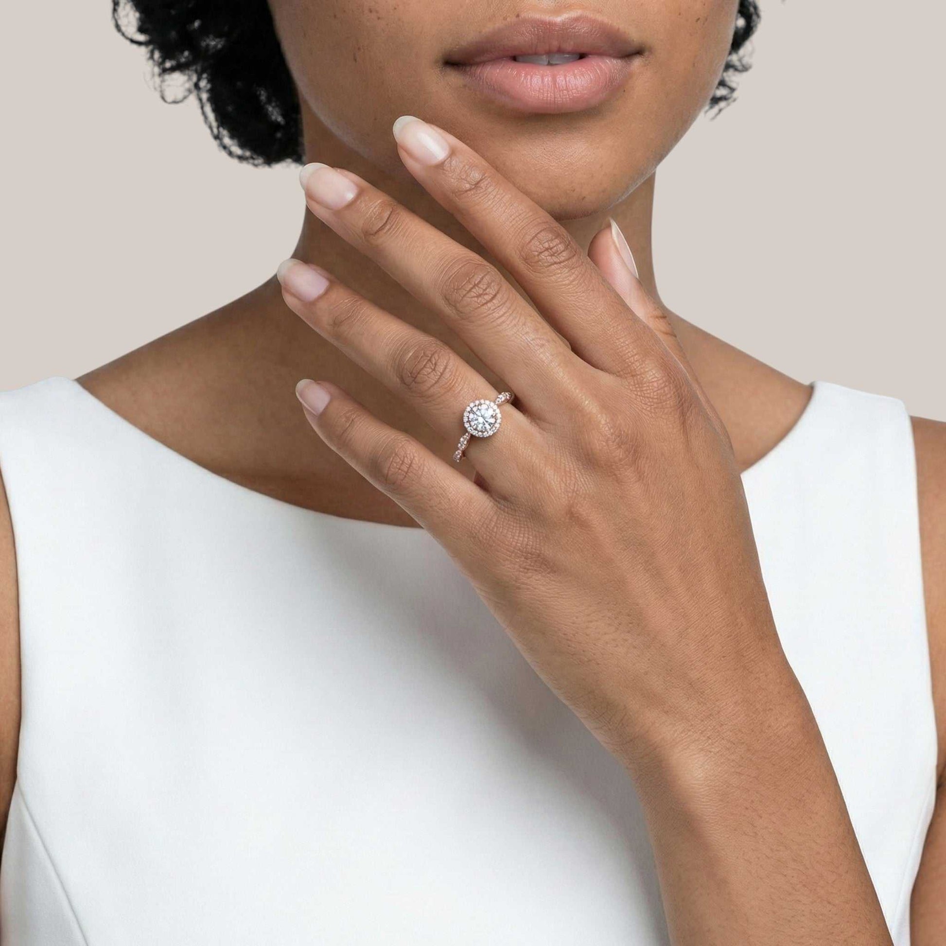 Close-up of a hand wearing a diamond ring with a plain background