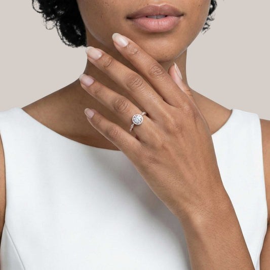 Close-up of a hand wearing a diamond ring with a plain background